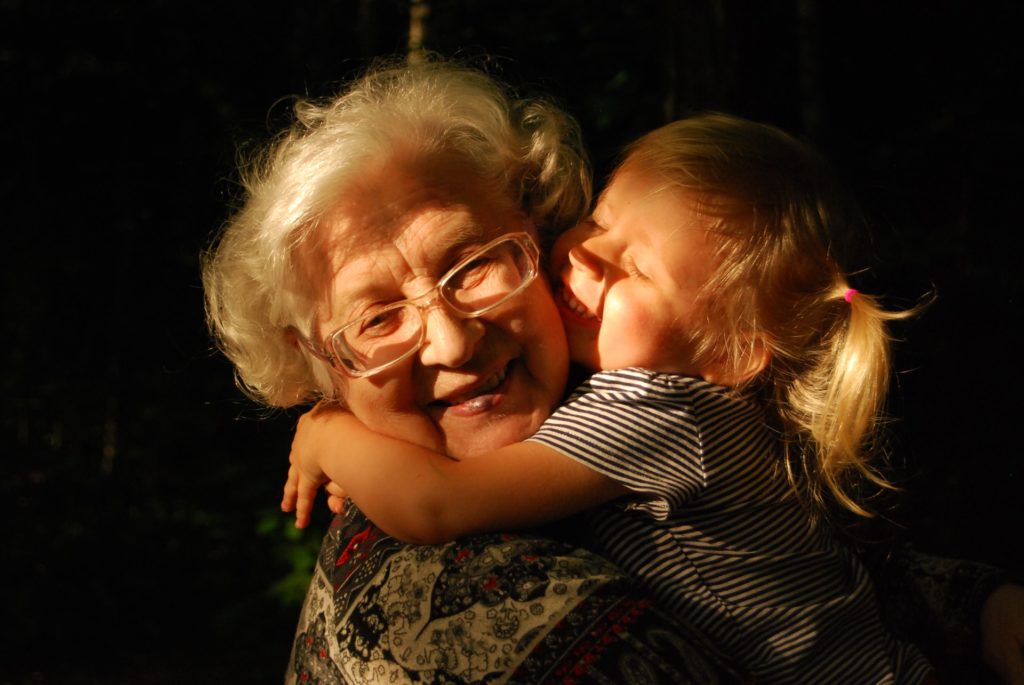 older woman being hugged by a young girl, representing a grandmother and her grandchild
